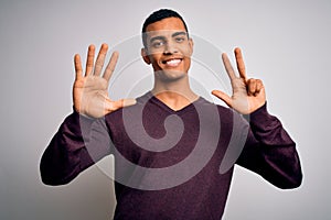 Young handsome african american man wearing casual sweater over white background showing and pointing up with fingers number eight