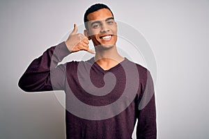 Young handsome african american man wearing casual sweater over white background smiling doing phone gesture with hand and fingers