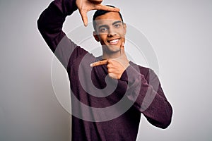 Young handsome african american man wearing casual sweater over white background smiling making frame with hands and fingers with