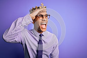 Young handsome african american man wearing golden crown of king over purple background very happy and smiling looking far away