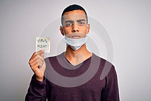 Young handsome african american man wearing medical mask holding virus alert reminder with a confident expression on smart face