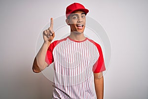 Young handsome african american sportsman wearing striped baseball t-shirt and cap pointing finger up with successful idea