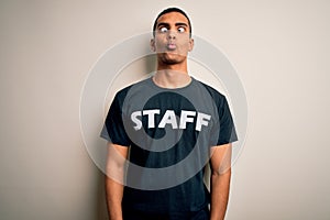 Young handsome african american worker man wearing staff uniform over white background making fish face with lips, crazy and