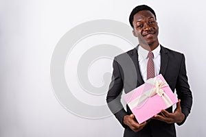 Young handsome African businessman holding gift box against whit