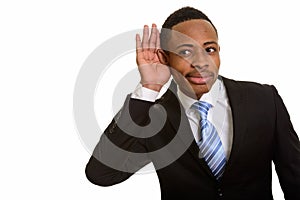 Young handsome African businessman listening and cupping ear