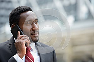 Young handsome African businessman talking on mobile phone