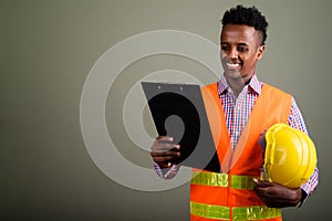 Young handsome African man construction worker against colored b