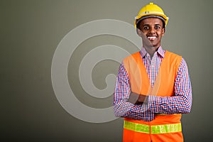 Young handsome African man construction worker against colored b