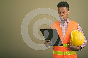 Young handsome African man construction worker against colored background