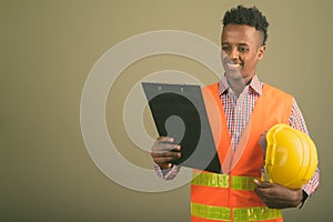 Young handsome African man construction worker against colored background