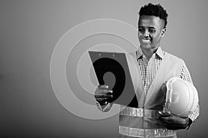 Young handsome African man construction worker against gray background