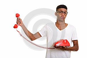 Young handsome African man looking annoyed while holding telepho