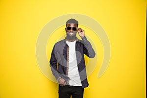 Young handsome african man in sunglasses on yellow background