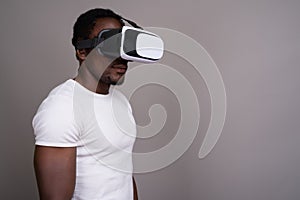 Young handsome African man using virtual reality headset against