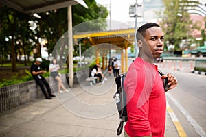 Young handsome African man waiting at the bus stop