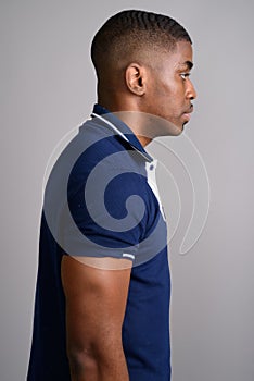 Young handsome African man wearing blue polo shirt against gray