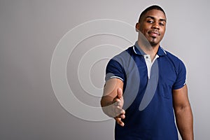 Young handsome African man wearing blue polo shirt against gray