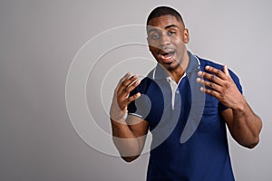 Young handsome African man wearing blue polo shirt against gray