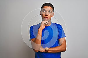Young handsome arab man wearing blue t-shirt standing over isolated white background with hand on chin thinking about question,