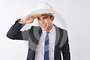 Young handsome architect man wearing suit and helmet over isolated white background very happy and smiling looking far away with