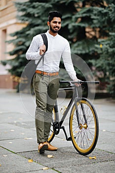 Young handsome asian business man with backpack walking down the street pushing bicycle while going to work