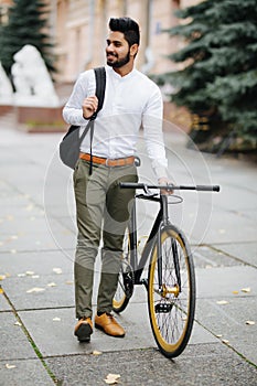 Young handsome asian business man with backpack walking down the street pushing bicycle while going to work