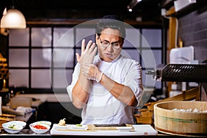 Young handsome Asian chef is putting on gloves before cooking rolles