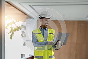 Young handsome asian engineer holding laptop looking forward and thinking, planning on construction building Evolution