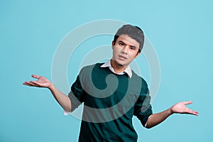 Young handsome Asian man over light blue background. He clueless and confused expression with arms and hands raised