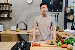 Young handsome asian man prepare salad food and cooking in the kitchen.