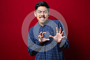 Young handsome asian man wearing casual shirt moving away hands palms showing refusal and denial with afraid and disgusting