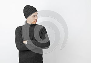 Young handsome asian man wearing grey sweater and beanie while arms crossed and looking up with happy face on white background.