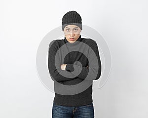 Young handsome asian man wearing grey sweater and beanie hugging herself and trembling, shaking from cold wind