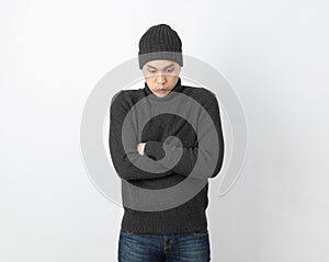 Young handsome asian man wearing grey sweater and beanie hugging herself and trembling, shaking from cold wind, freezing on white