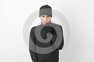 Young handsome asian man wearing grey sweater and beanie trembling, shaking from cold wind, freezing on white background.