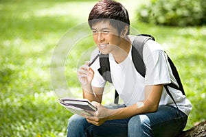 Young handsome Asian student with books and smile in outdoor