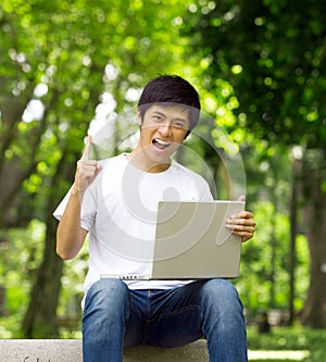 Young handsome Asian student with laptop