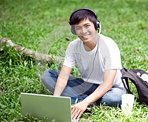 Young handsome Asian student with laptop and smile in outdoor