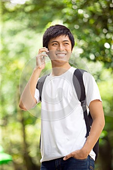 Young handsome Asian student talking on cell phone