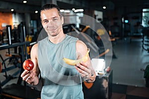 young handsome athlete hungry and eating healthy apple fruit in gym