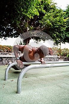 Young handsome athlete man doing calisthenics exercises on bars in park. Outdoor gym. Healthy lifestyle. Sport. Hobby