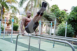 Young handsome athlete man doing calisthenics exercises on bars in park. Outdoor gym. Healthy lifestyle. Sport. Hobby