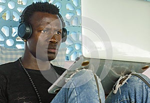 Young handsome and attractive black afro American man working with laptop computer and headphones concentrated and thoughtful in