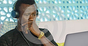 Young handsome and attractive black afro American man working with laptop computer and headphones concentrated and thoughtful in