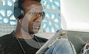 Young handsome and attractive black afro American man working with laptop computer and headphones concentrated and thoughtful in