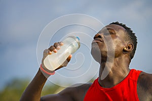 Young handsome and attractive black afro American sport man tired and thirsty after running workout holding bottle drinking water