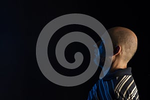 Young handsome bald man with beard wearing casual shirt over black background