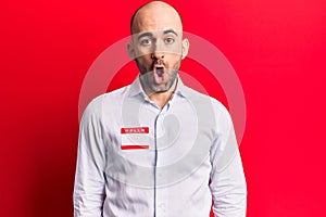 Young handsome bald man wearing hello my name is sticker scared and amazed with open mouth for surprise, disbelief face