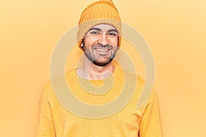 Young handsome bald man wearing sweater and wool cap with a happy and cool smile on face