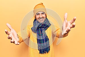 Young handsome bald man wearing winter clothes looking at the camera smiling with open arms for hug